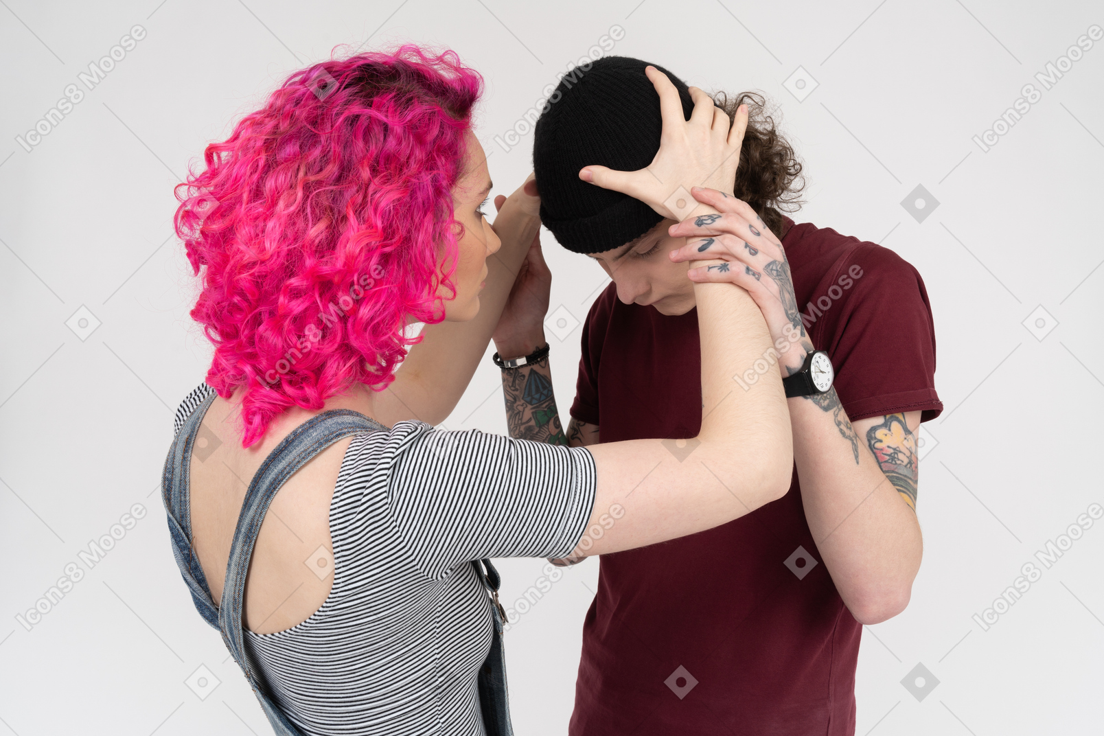 Pink-haired girl putting black hat on her boyfriend