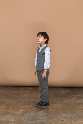 Side view of a boy in grey suit making faces