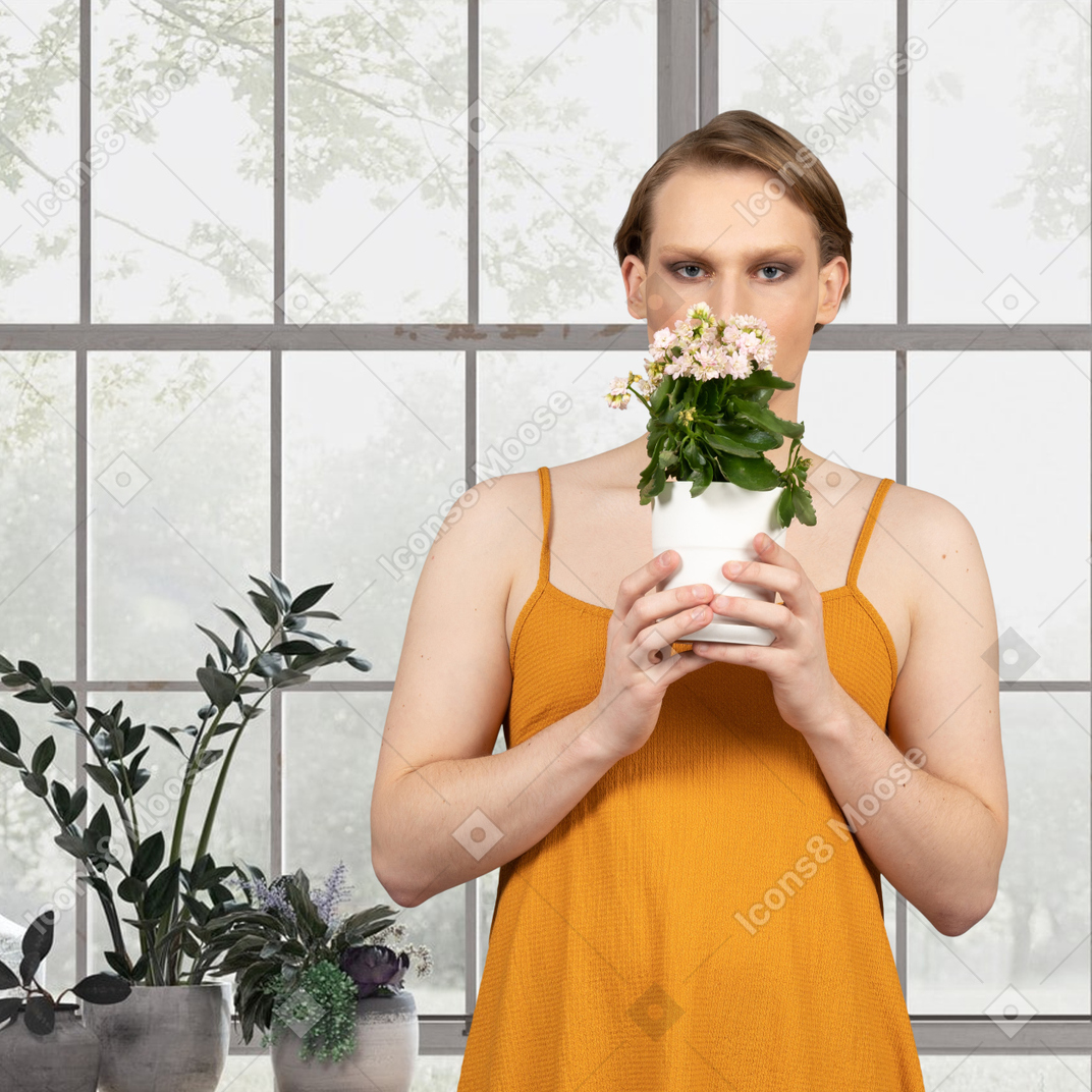 A woman holding a potted plant in the greenhouse