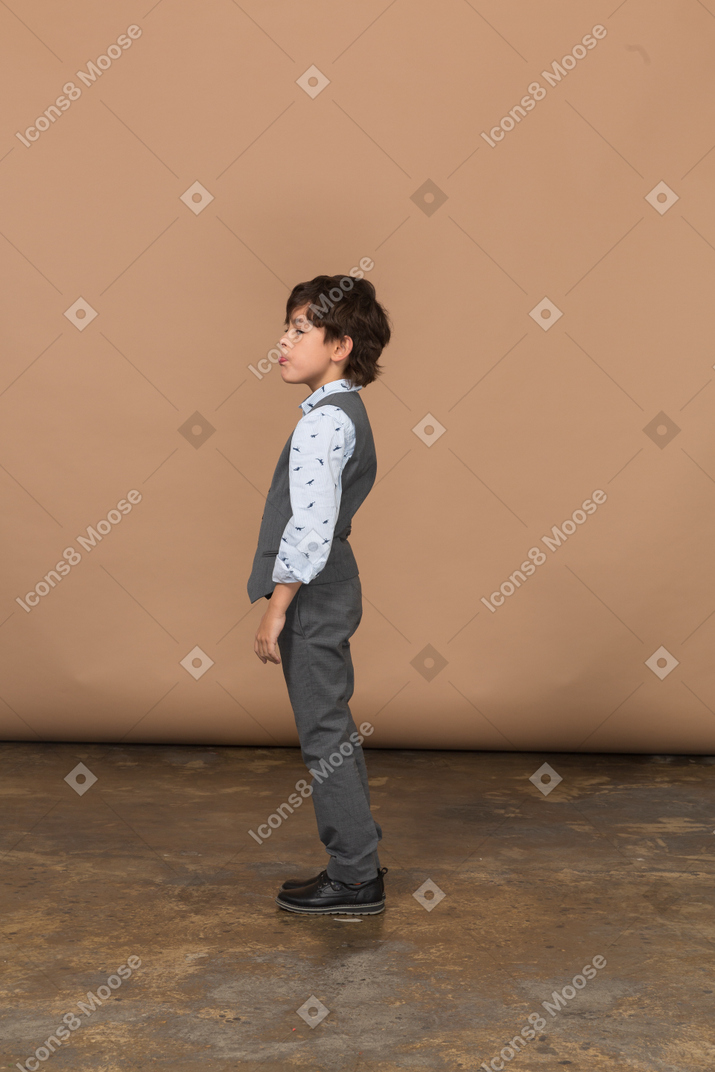 Vista laterale di un ragazzo carino in abito grigio