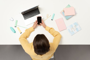 A female office worker at the table holding phone