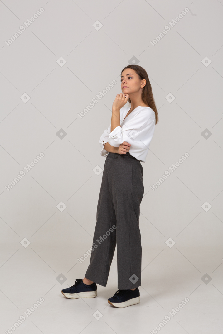 Вид в три четверти задумчивой молодой леди в офисной одежде, трогающей подбородок