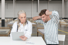 Puzzled man and doctor looking at tablet