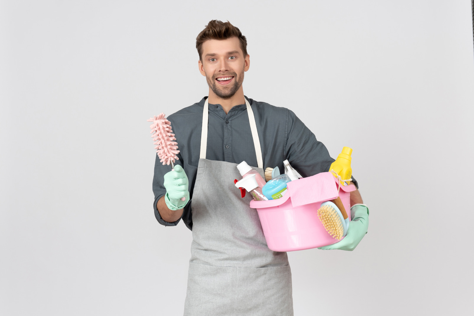 Young househusband holding wasin with cleaning utensils and brush