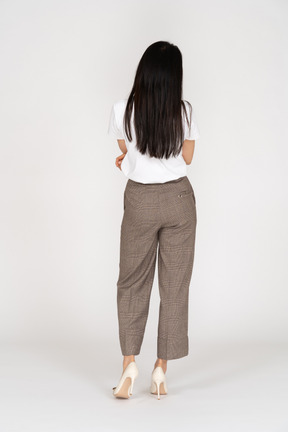 Vista posteriore di una giovane donna scontenta in calzoni e maglietta che attraversano le mani