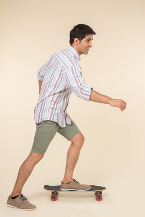 Young caucasian guy standing in profile on skate