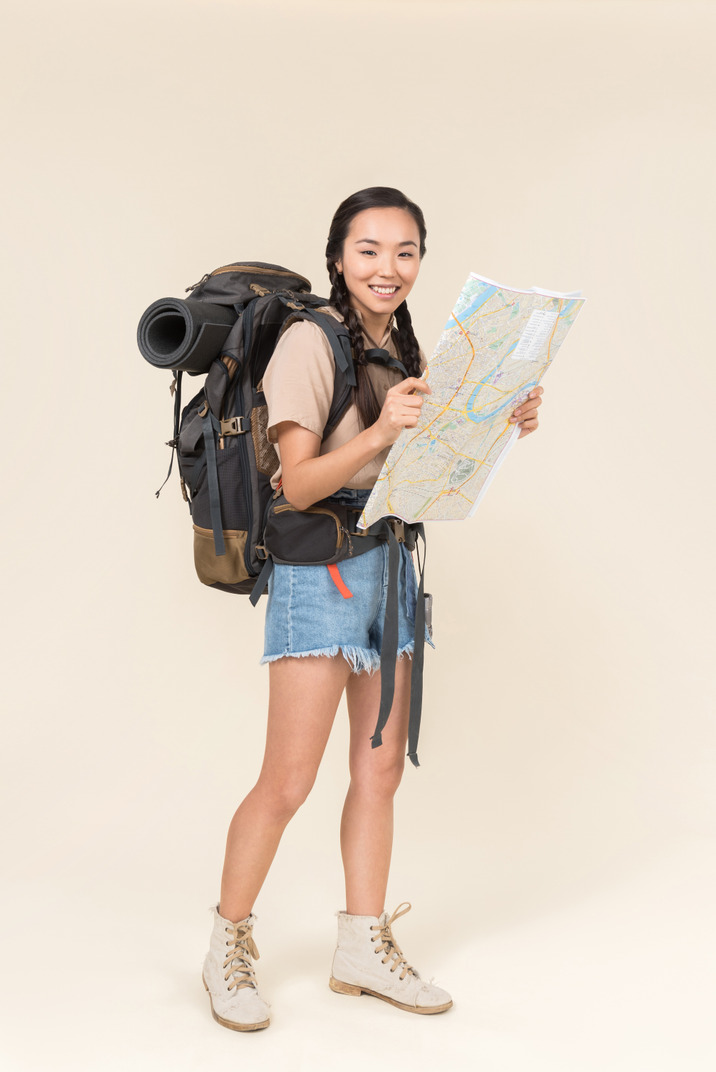 Young asian hiker holding a map looks happy