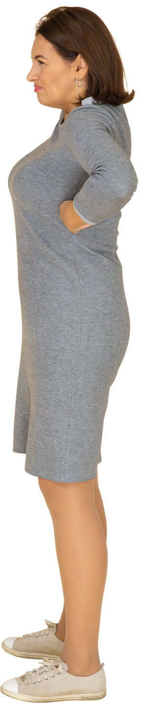 Vue latérale d'une femme en robe grise posant