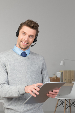 A man wearing a headset and holding a tablet