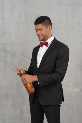 Well-dressed man opening a champagne bottle