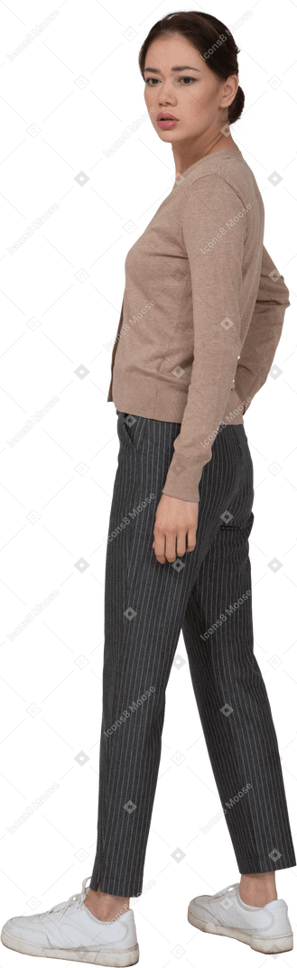 Vista laterale di una giovane donna preoccupata in pullover e pantaloni che voltano le spalle