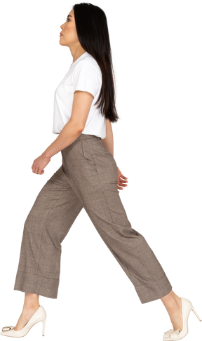 Vista laterale di una giovane donna che cammina in calzoni e t-shirt