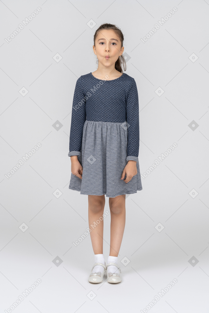 Vista frontal de una niña de pie con las mejillas hundidas