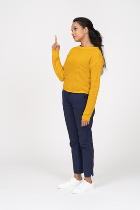 Front view of a girl in casual clothes pointing up with a finger