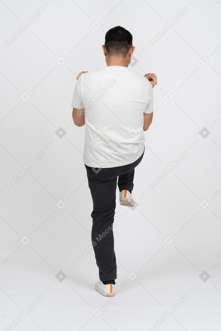 Vista traseira de um homem em roupas casuais em pé em uma perna com