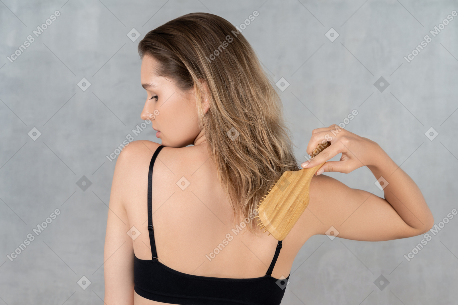 Vista traseira de uma jovem escovando o cabelo