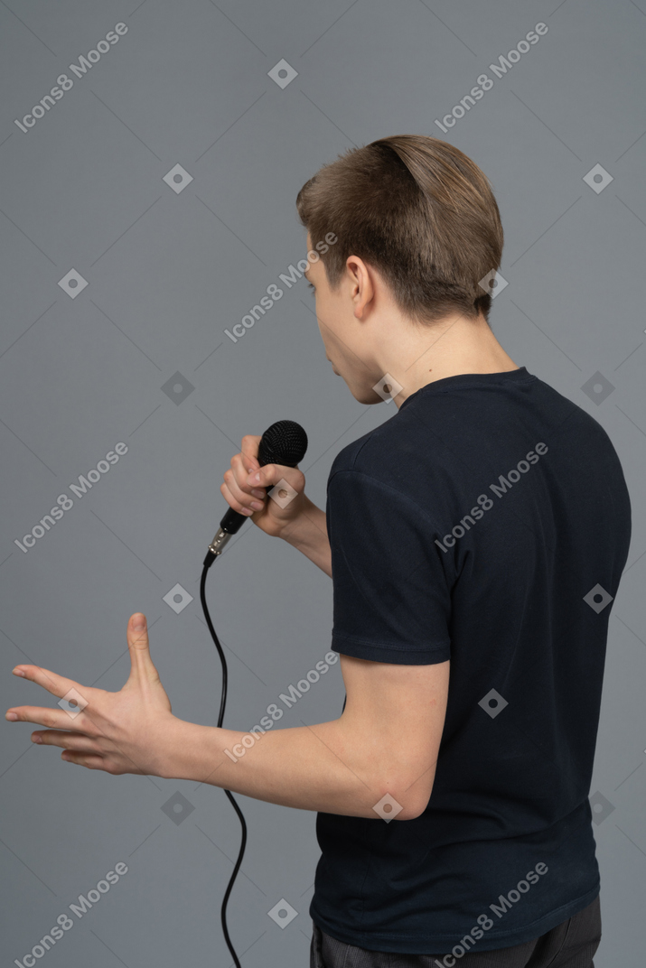 Junger mann gestikuliert beim sprechen ins mikrofon