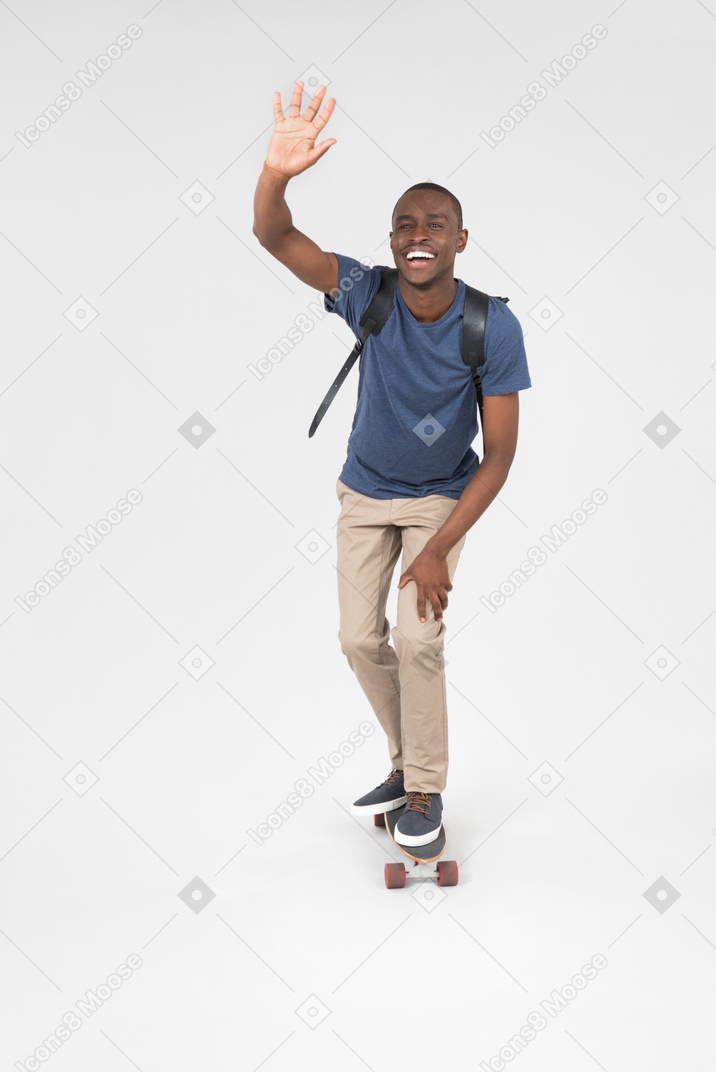 Smiling male tourist standing on skateboard and skating
