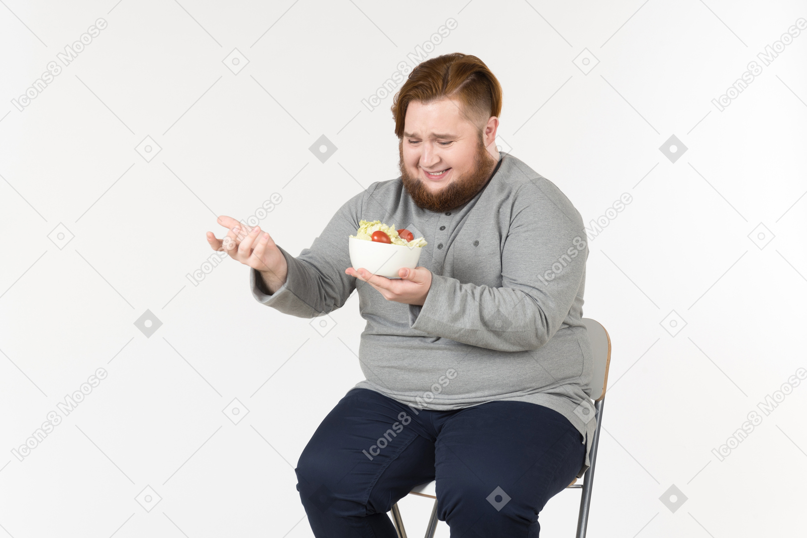 Laughing big bearded man sitting and holding salad