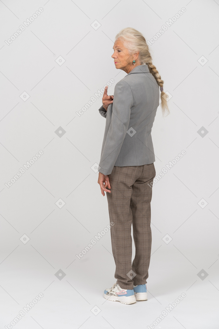 Rear view of an old woman in suit pointing with a finger