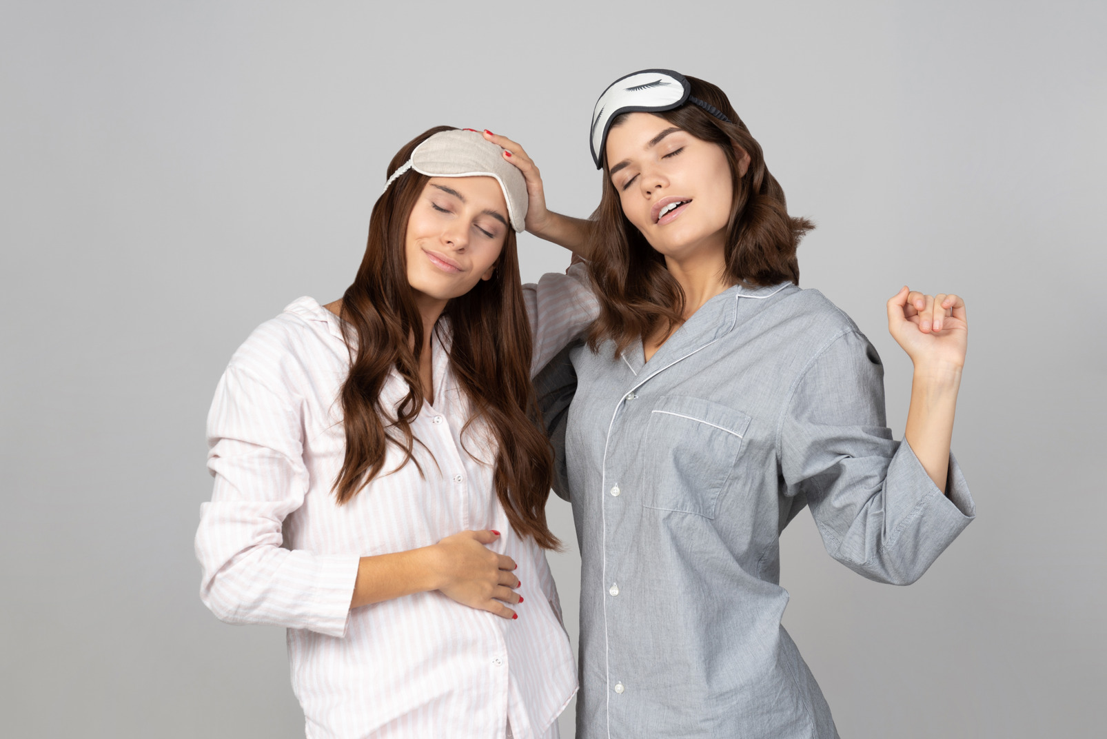 Sleepy young women wearing sleep masks and pyjamas