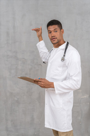 A male doctor holding a clipboard and gesturing