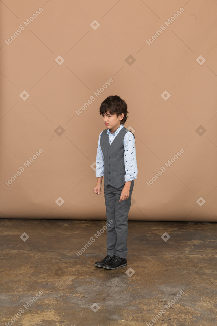 くいしばられた握りこぶしで立っているスーツを着た少年の正面図
