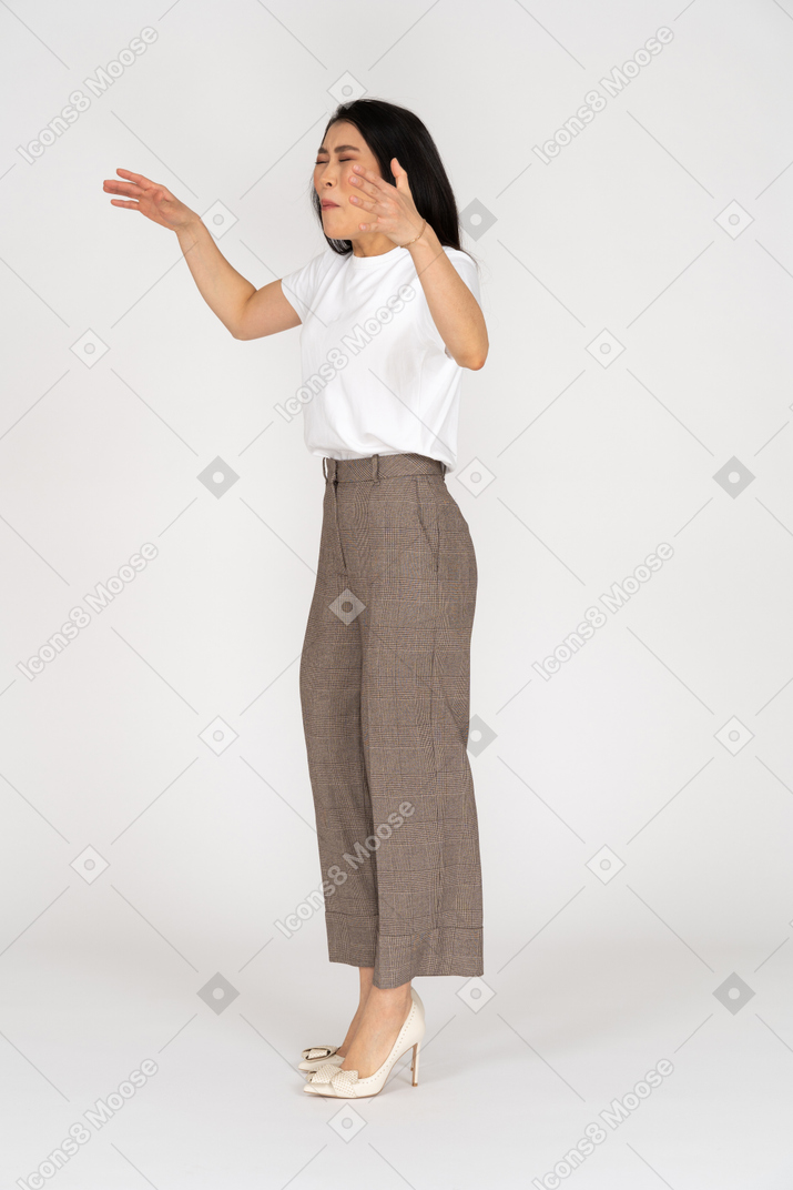 Three-quarter view of a naughty young lady in breeches and t-shirt raising her hands