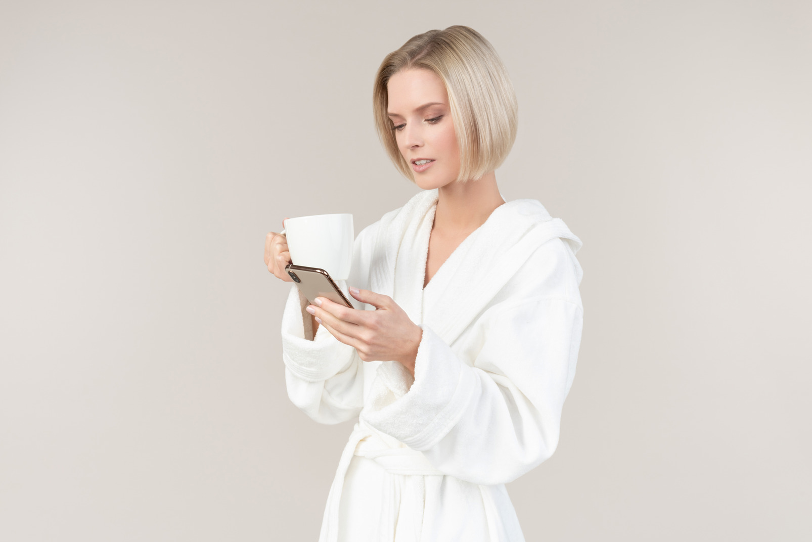 Young woman using phone and having morning coffee