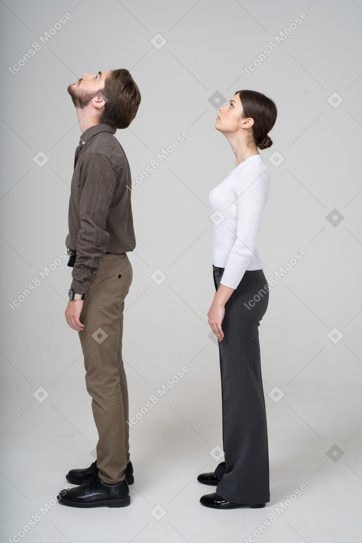 Vista lateral de um jovem casal com roupas de escritório, olhando para cima