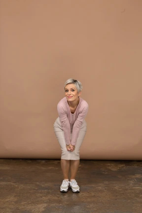 Front view of a woman in casual clothes posing with hands on knees