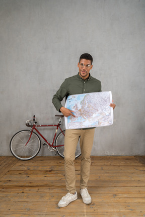 Front view of a man holding and pointing at a map