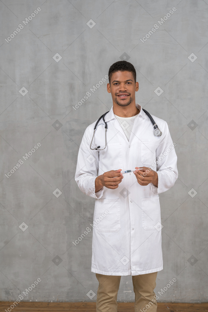 Smiling male doctor holding a thermometer