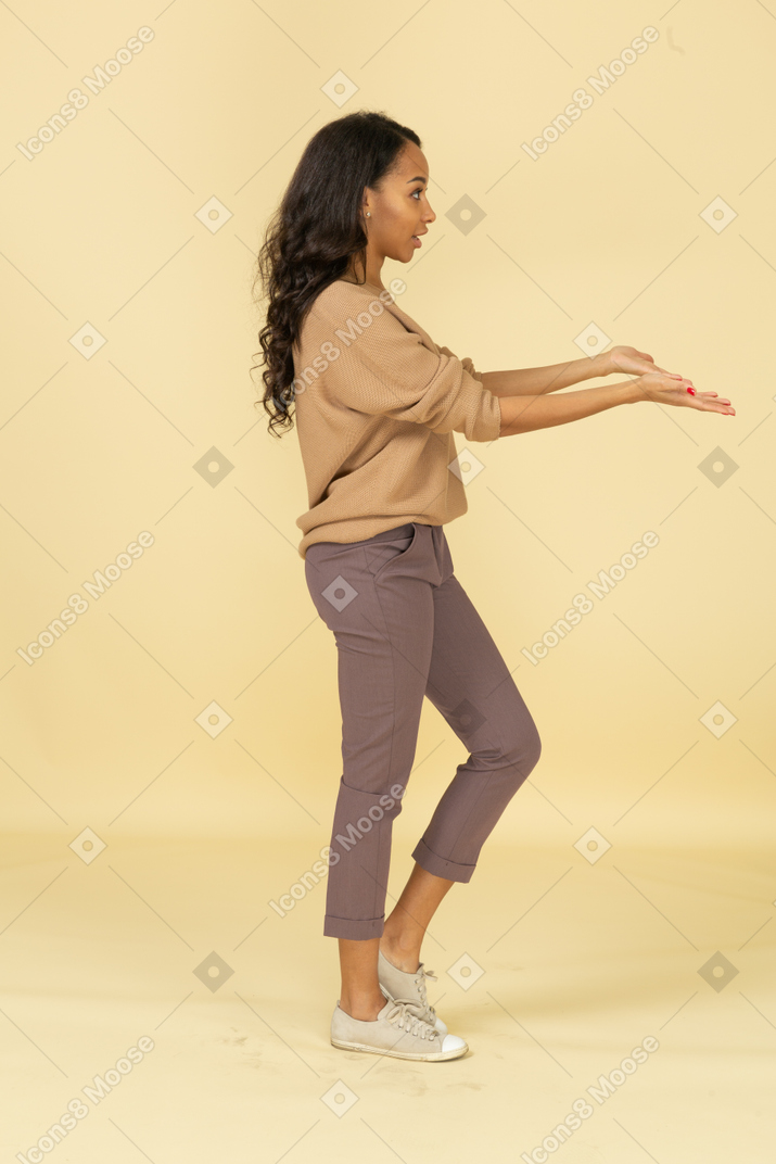 Side view of a questioning dark-skinned young female outstretching hands