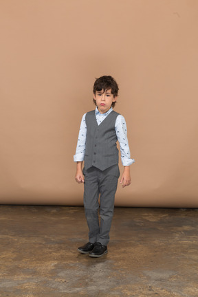 Vista frontal de un niño con traje gris mirando a la cámara