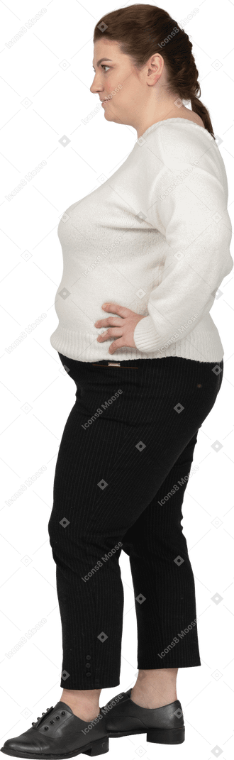 Plus size frau im weißen pullover stehend mit den händen auf den hüften
