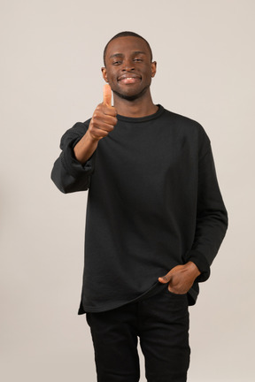 Молодой человек в черной одежде показывает палец вверх