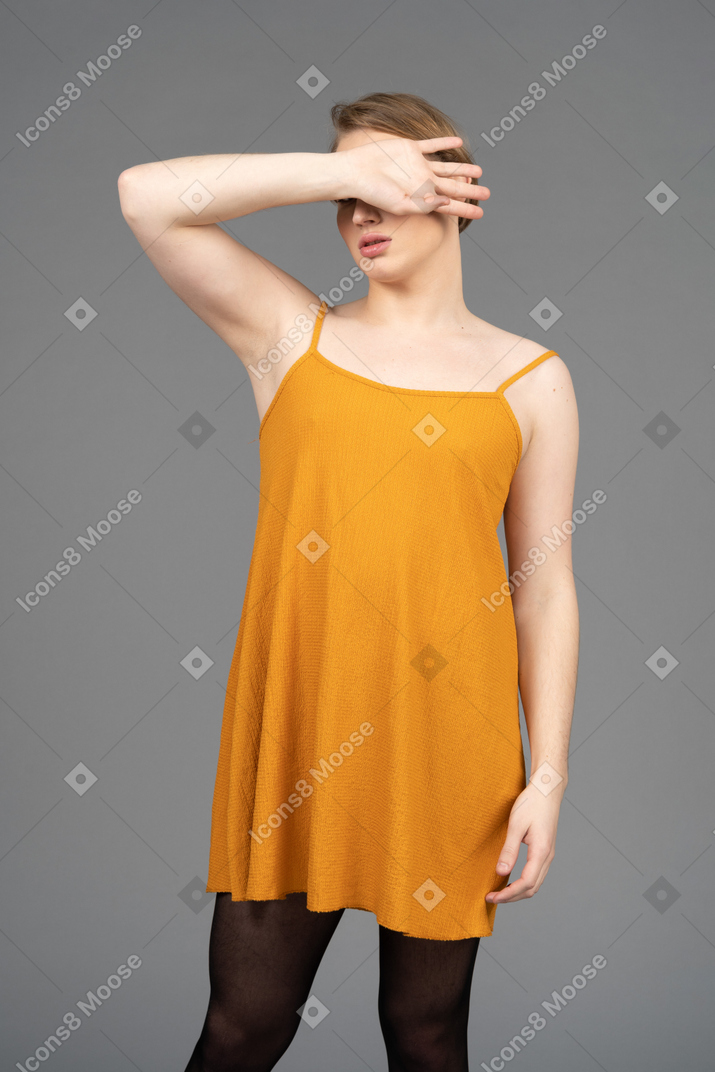 Genderqueer person covering face with back of hand