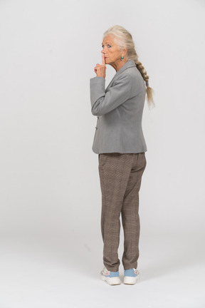 Rear view of an old lady in suit making a shh gesture