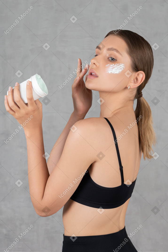 Jeune femme hydratant son visage avec de la crème