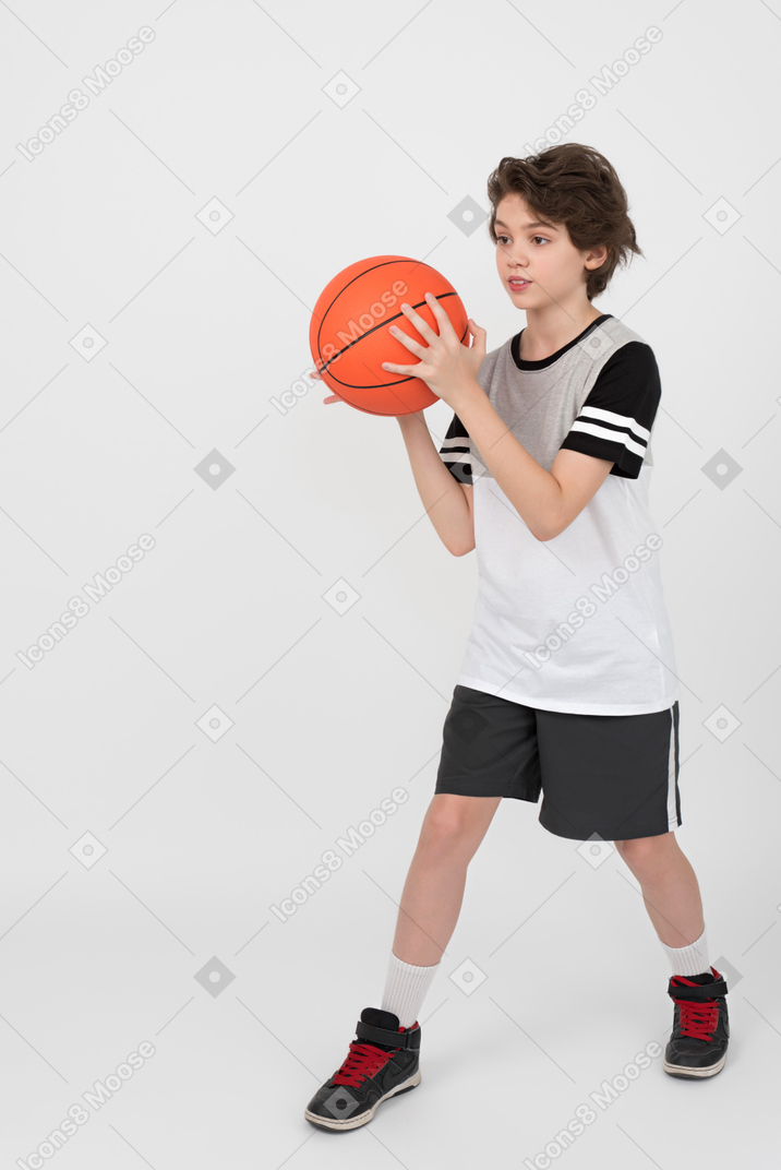 深刻な顔を持つ少年はボールを投げるつもりです