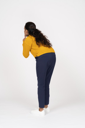 Rear view of a girl in casual clothes making shhh gesture