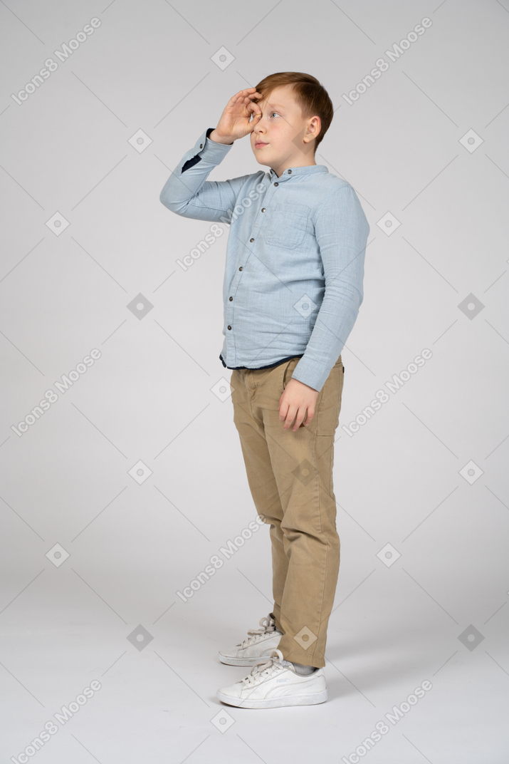 一个男孩通过假想的双筒望远镜看的侧视图
