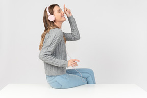 Jeune femme assise sur la table et écoute de la musique au casque