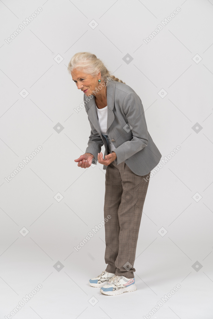 Seitenansicht einer alten dame im anzug, die sich bückt und etwas erklärt