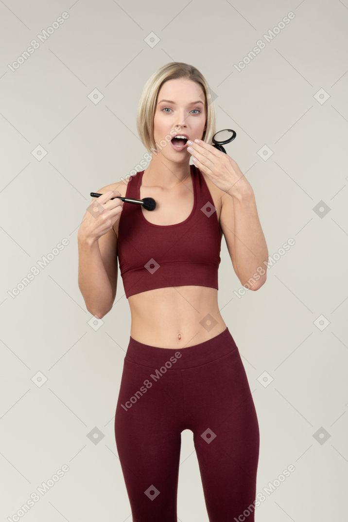 Jadeando mujer en ropa deportiva contorneando a sí misma abs
