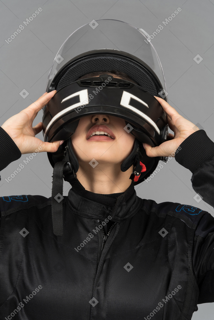 A young woman taking off a black helmet