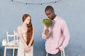 A man is holding a bouquet of flowers for a woman