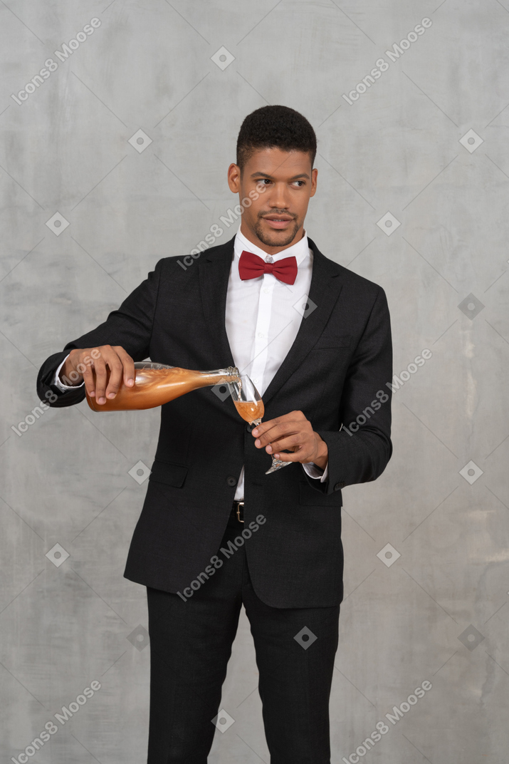 Front view of young man filling a flute glass with spirits