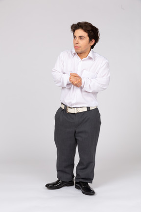 Front view of young man standing with clasped hands